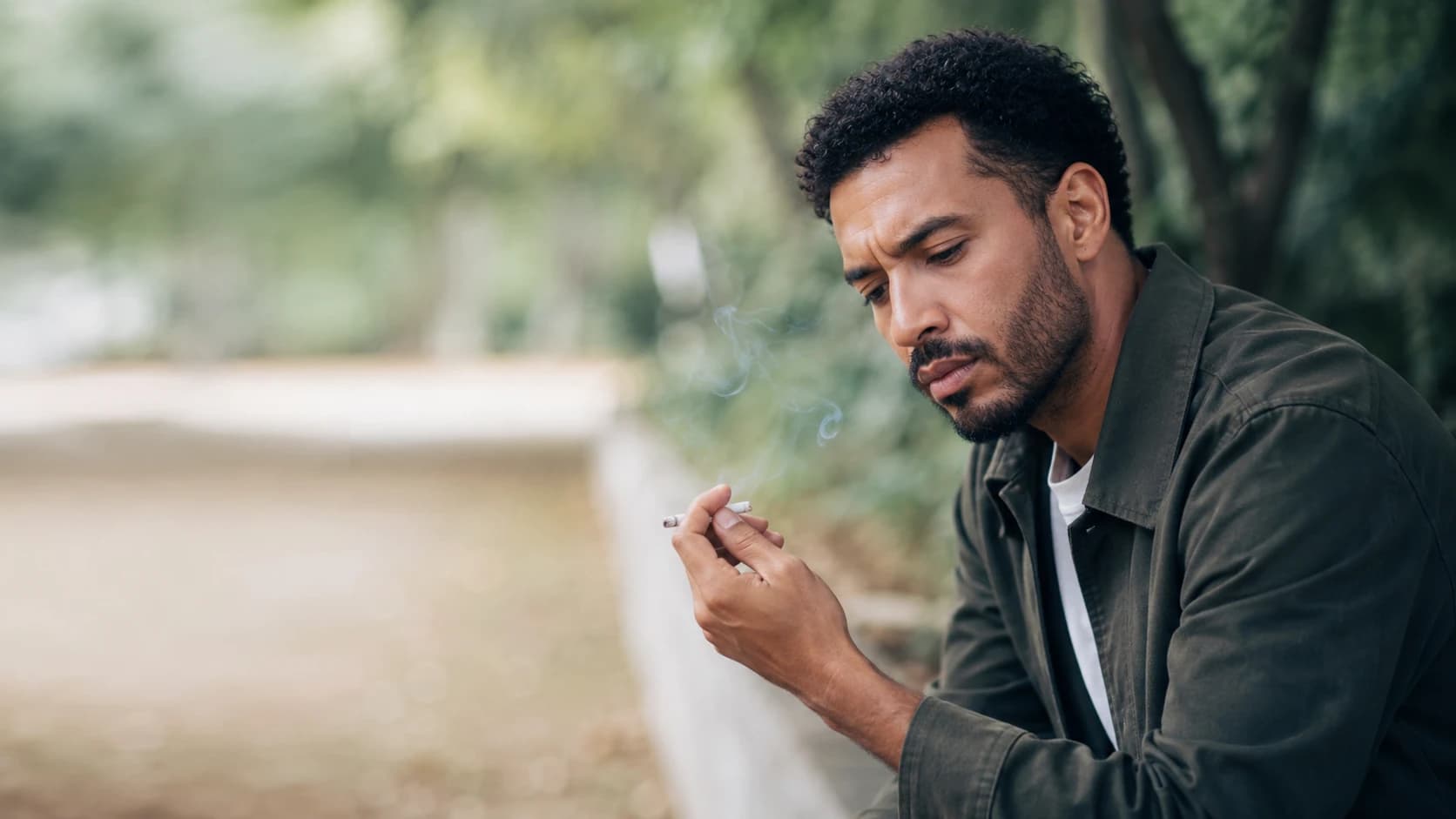 Pessoa olhando um cigarro entre os dedos com hesitação, com vontade de largar.